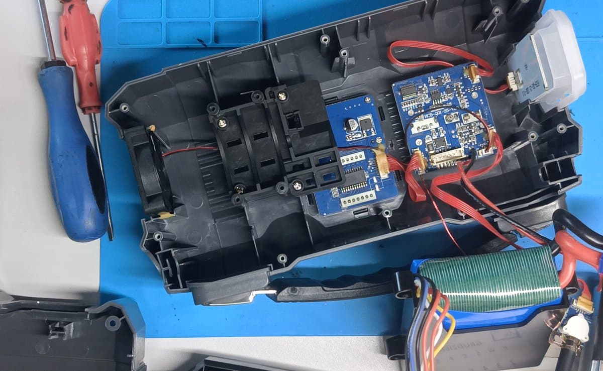 Rozebrany jump starter Mikavi na macie warsztatowej - widoczne płytki elektroniki, akumulator i okablowanie